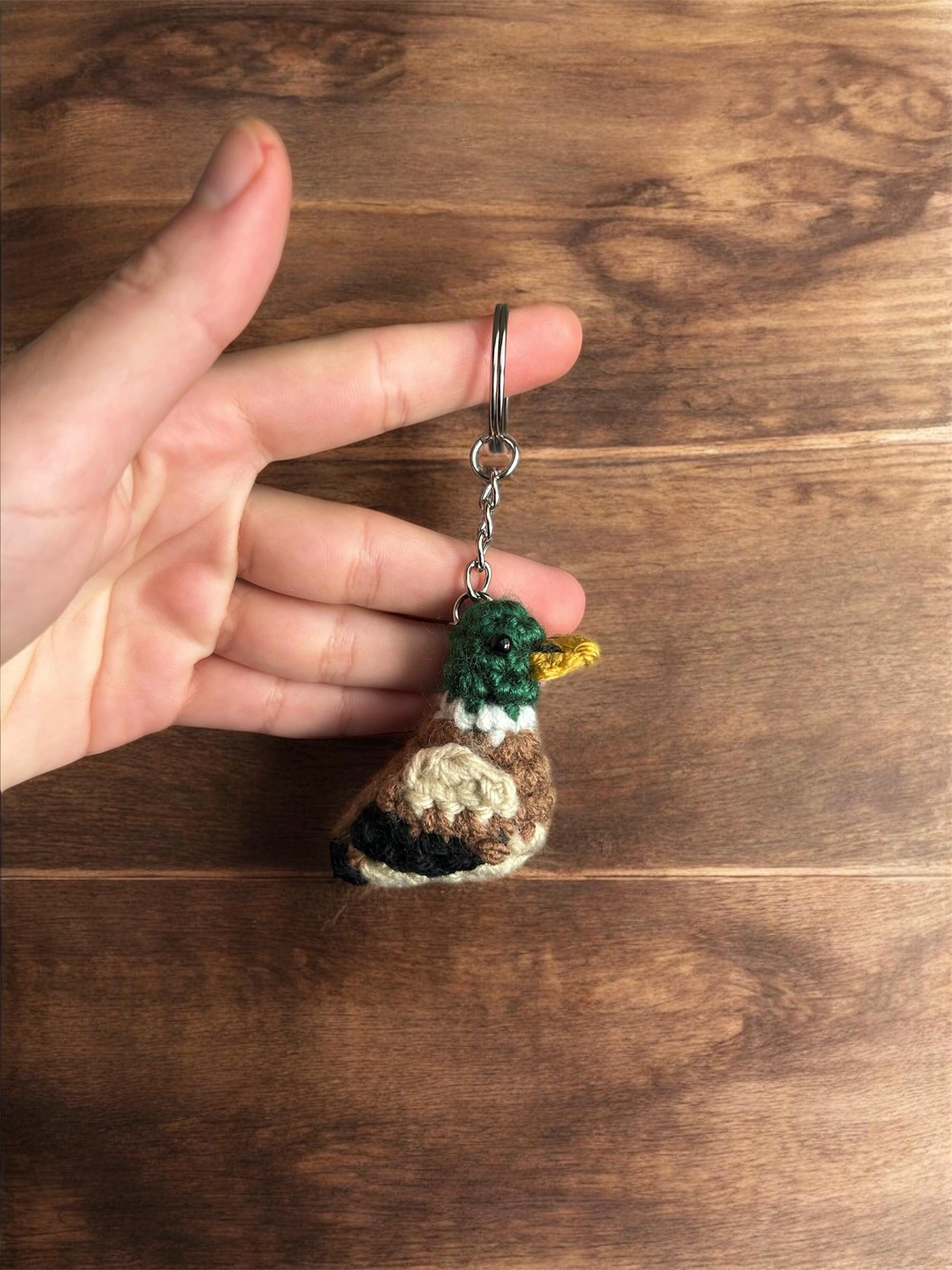 Hand holding a small crocheted keychain with a wooden background