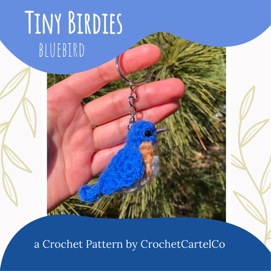A bluebird keychain crochet pattern shown with a blue background and greenery.