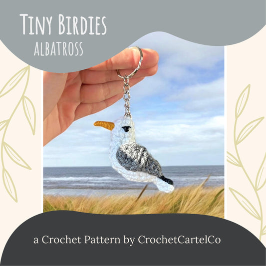 Crocheted albatross keychain crochet pattern, shown held in a hand with a scenic background