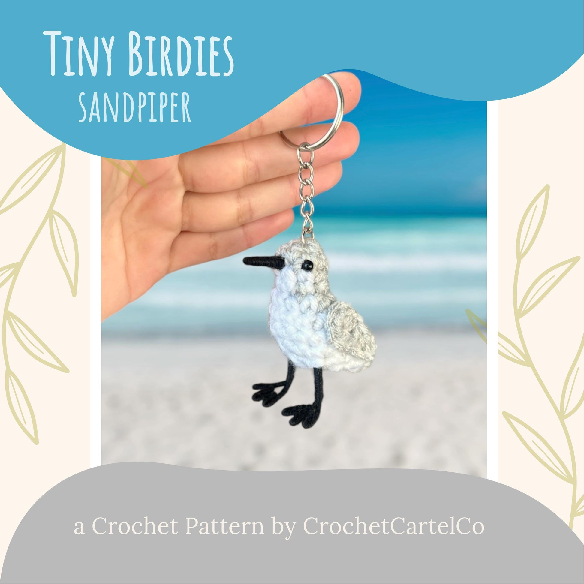 Hand holding a crochet sandpiper keychain with a beach background, featuring 'Tiny Birdies Sandpiper, a crochet pattern by CrochetCartelCo'