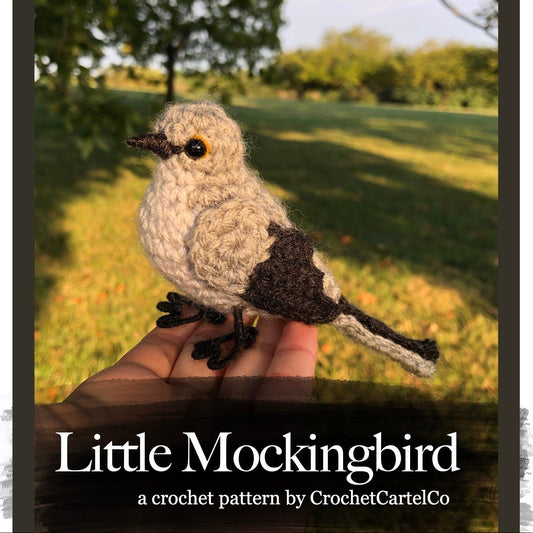 Crocheted mockingbird pattern, held in a hand with a natural background