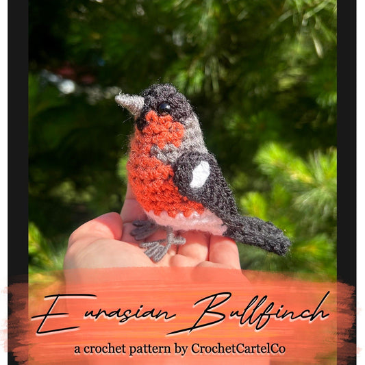 Crocheted Eurasian Bullfinch crochet pattern, shown held in a hand with a blurred green background