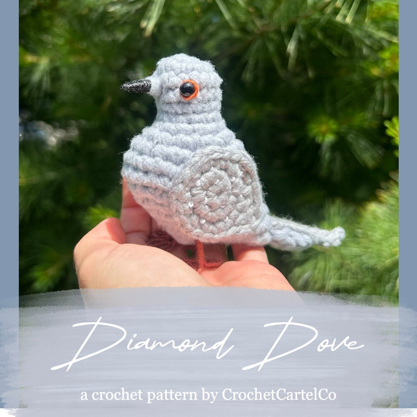Crocheted diamond dove pattern, shown held in a hand with a blurred green background