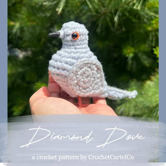 Crocheted diamond dove pattern, shown held in a hand with a blurred green background
