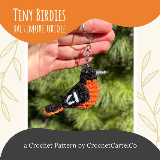 Baltimore Oriole keychain Crochet Pattern shown in front of green foliage