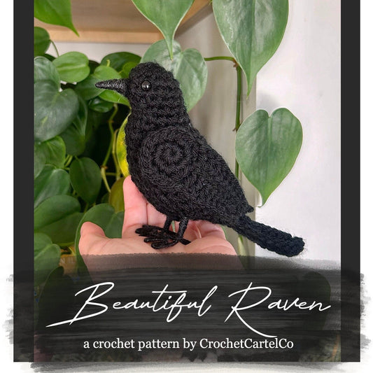 Crochet pattern for a raven held in a hand with green leaves in the background, featuring 'Beautiful Raven' crochet pattern by CrochetCartelCo.