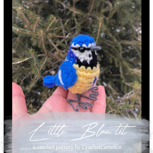 A crocheted blue tit bird crochet pattern shown with a snowy branch background, featuring the brand 'CrochetCartelCo'.
