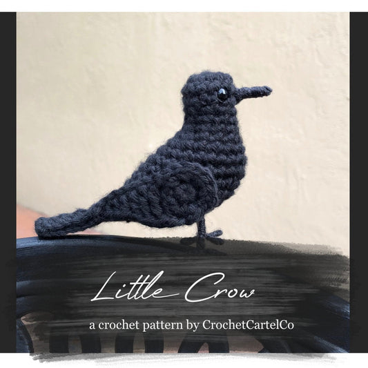 Crocheted bird pattern titled 'Little Crow' by CrochetCartelCo on a textured beige background.