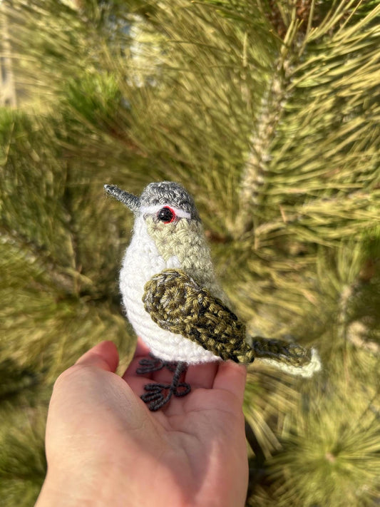 Crocheted bird held in a hand with a blurred natural background