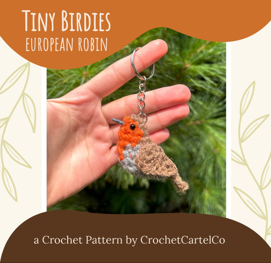 Hand holding a crochet keychain of a European Robin bird against a green leafy background, with text about the crochet pattern by CrochetCartelCo.